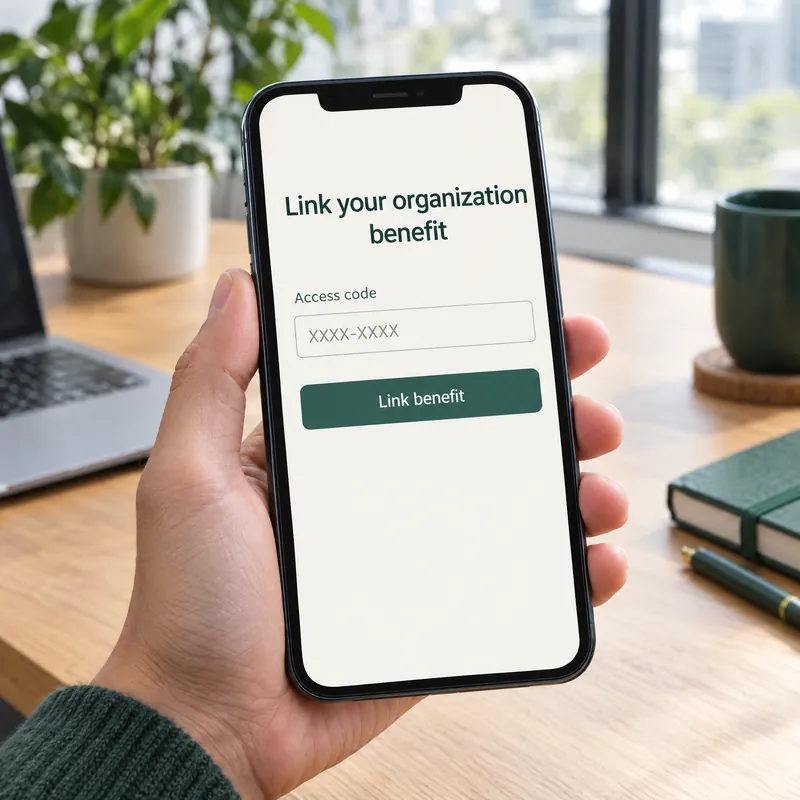 A hand holds a phone showing the screen to link an organization benefit, with an access code field and a Link benefit button